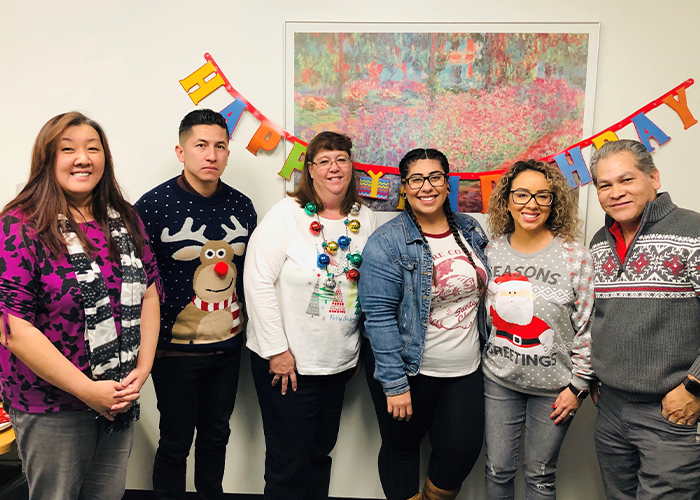 Employees together wearing holiday sweaters.